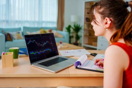 Une jeune femme étudie un graphique en chandeliers d’un investissement possible