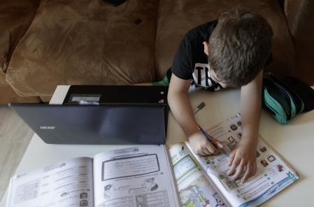 Un étudiant primaire fait les fonctions de la matière anglaise avec plusieurs livres et un ordinateur moins d'un mois après la fin de l'année scolaire 2019-2020 pour la pandémie Covid-19, à Madrid (Espagne) au 20 mai 2020.